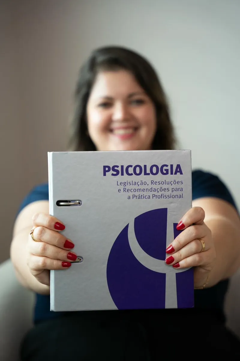 Psicóloga Lis Caroline Consani segurando livro de TCC